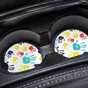 Autism Awareness ceramic car coasters displayed inside vehicle cup holders with colorful kids artwork.