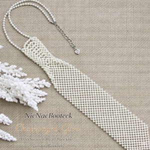Handwoven pearl beaded necktie in Champagne Glow on neutral linen background