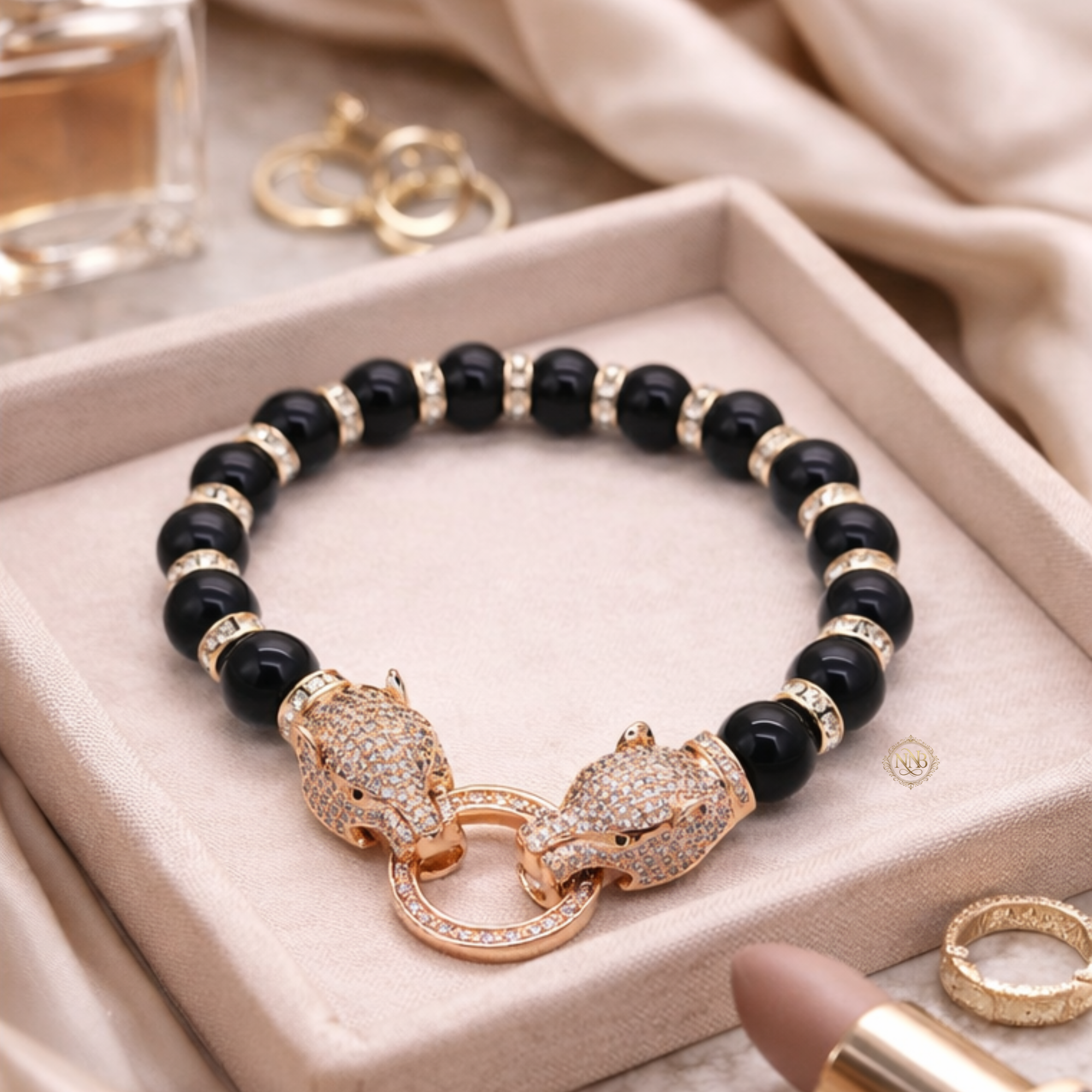 Black onyx beaded bracelet with crystal-detailed panther clasp in a rose-tone finish, displayed on a neutral jewelry tray.