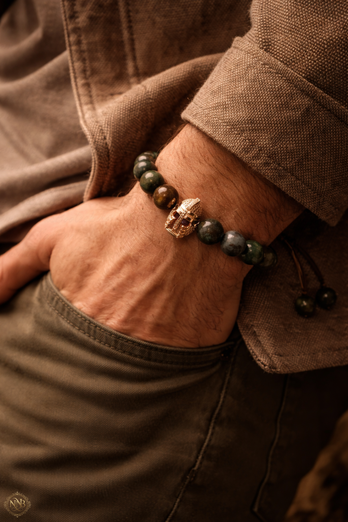 Editorial lifestyle image of a man wearing 12mm natural agate stone bracelet with rose gold warrior helmet centerpiece.