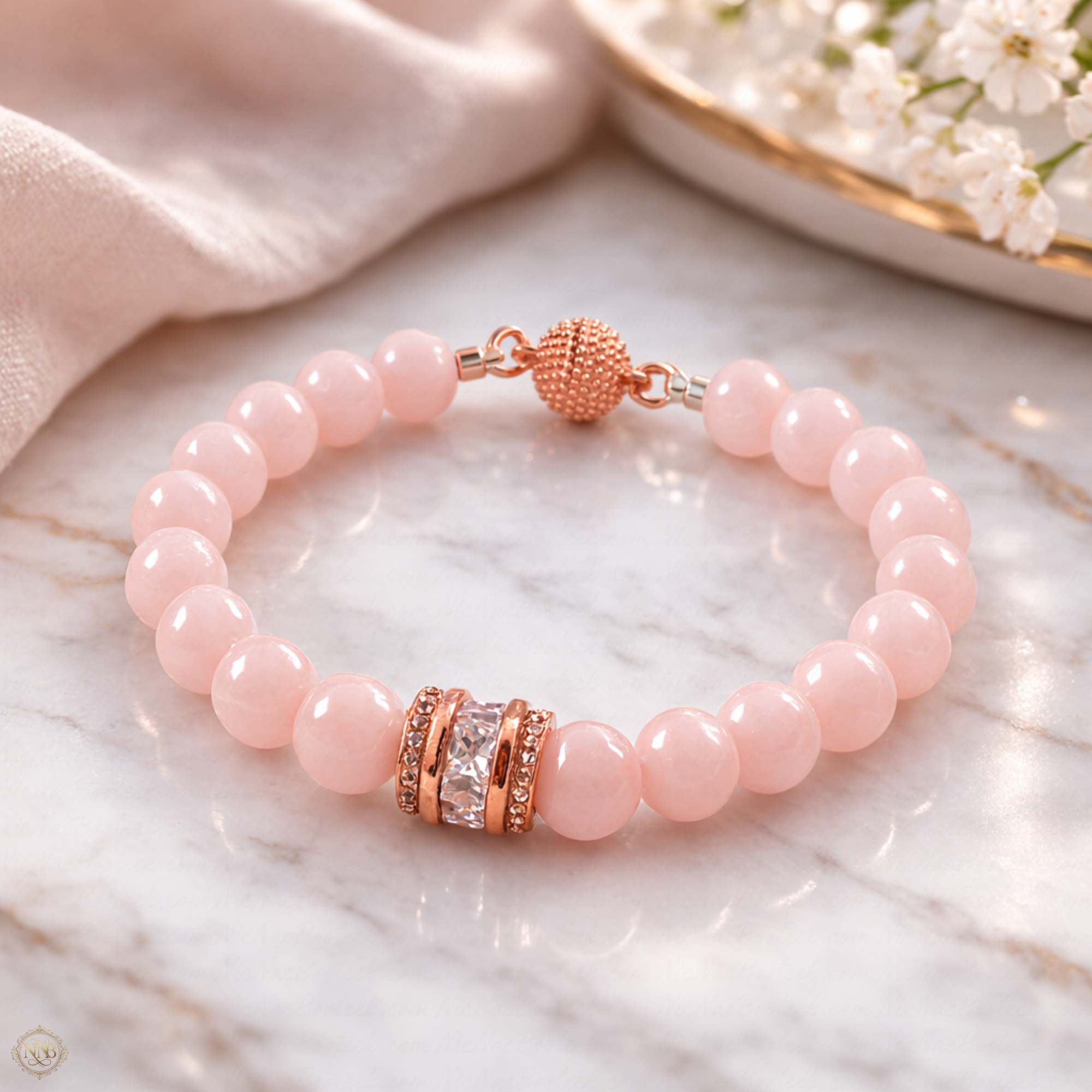 Light pink jade chalcedony beaded bracelet with rose gold crystal focal and magnetic clasp on marble background.