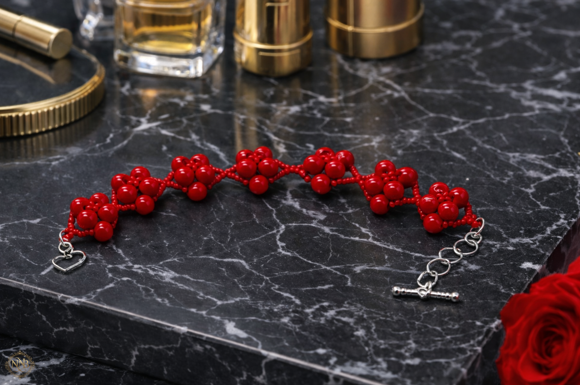 Bold red handwoven bead bracelet with silver heart toggle clasp photographed on black marble, structured statement jewelry for women