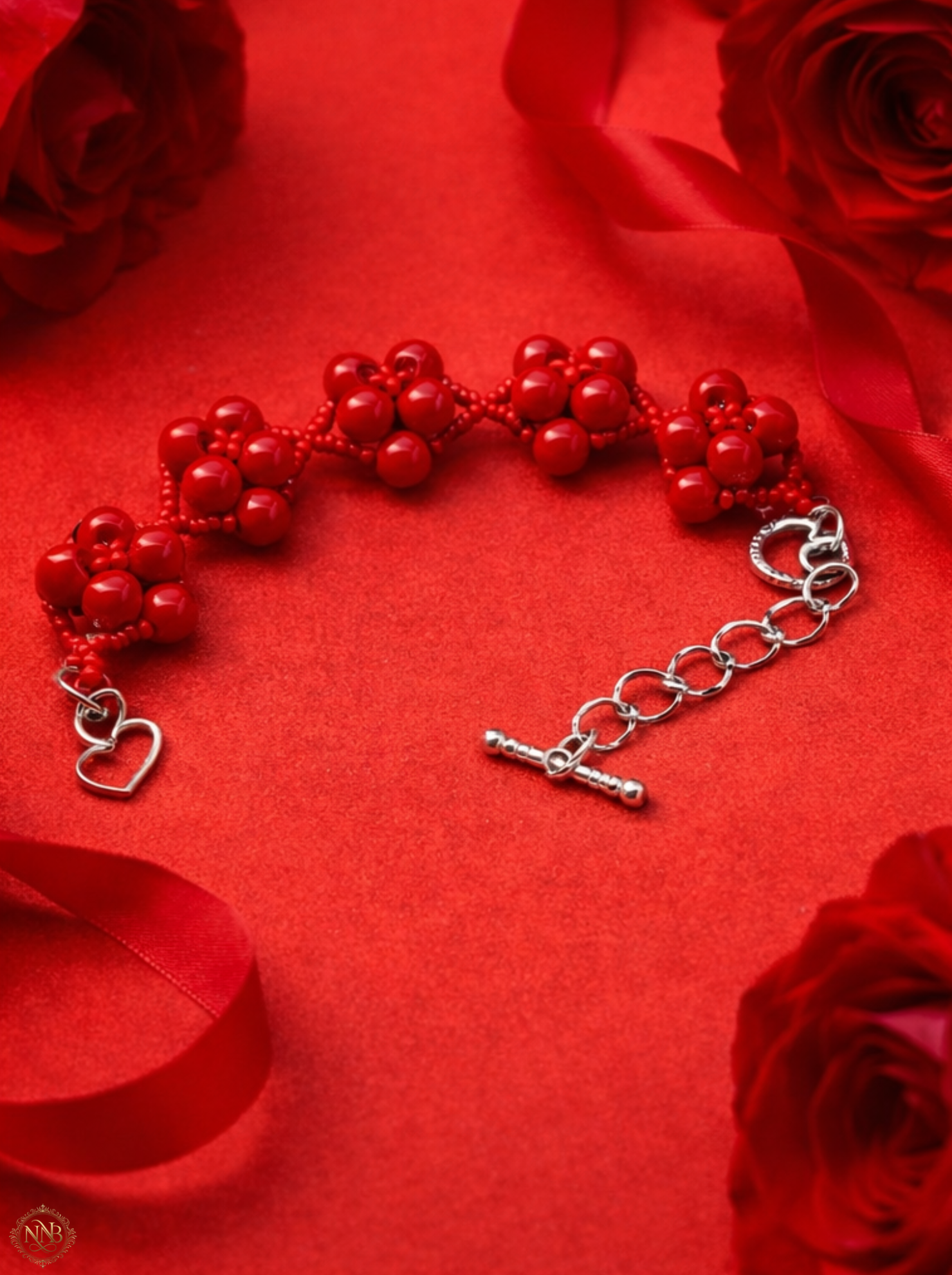 7.5 inch handmade red beaded bracelet with dimensional cluster design and silver heart toggle clasp styled on soft linen surface for luxury jewelry display