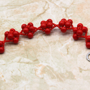 7.5 inch handcrafted red cluster bead bracelet with silver heart toggle closure photographed on neutral marble surface, bold women’s statement jewelry
