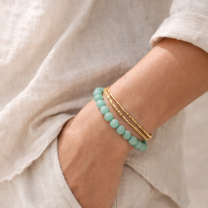 Adjustable 8mm green stone bracelet worn on wrist layered with gold bangles