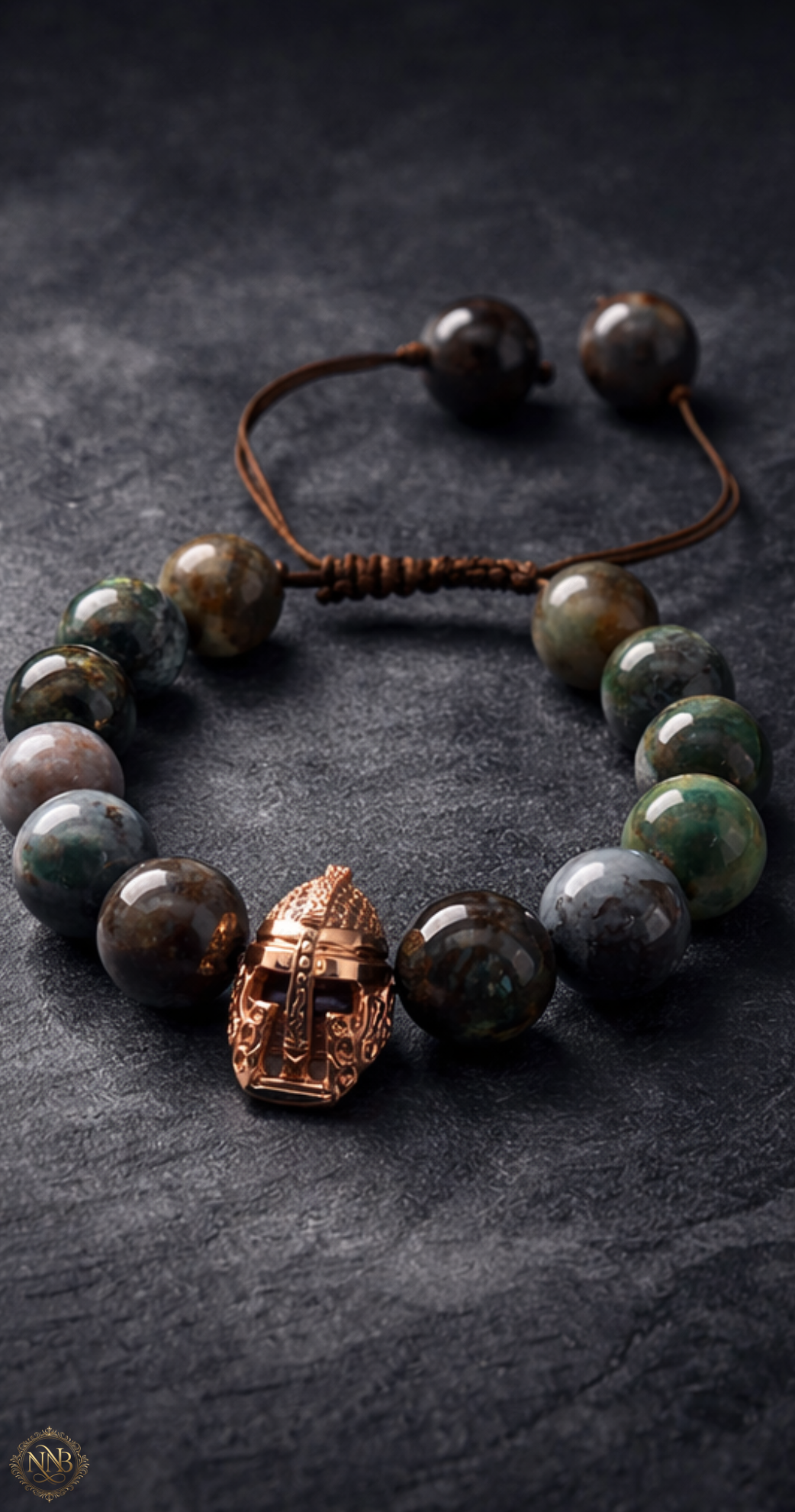 12mm natural agate stone bead bracelet with adjustable brown cord and rose gold tone Viking helmet centerpiece, photographed on a dark textured surface with dramatic lighting.